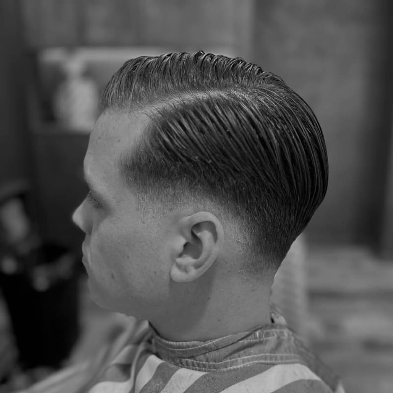 Man with a classic low fade side part haircut featuring neatly combed hair and a sharp fade above the ears, perfect for a clean, professional men's hairstyle.