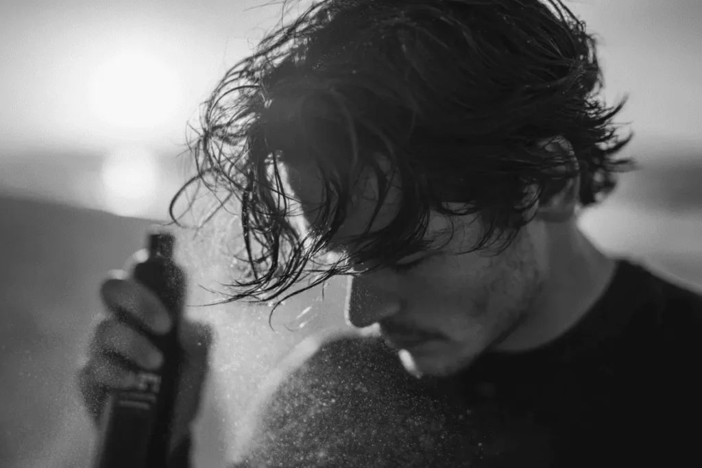 Man applying sea salt spray to damp hair.