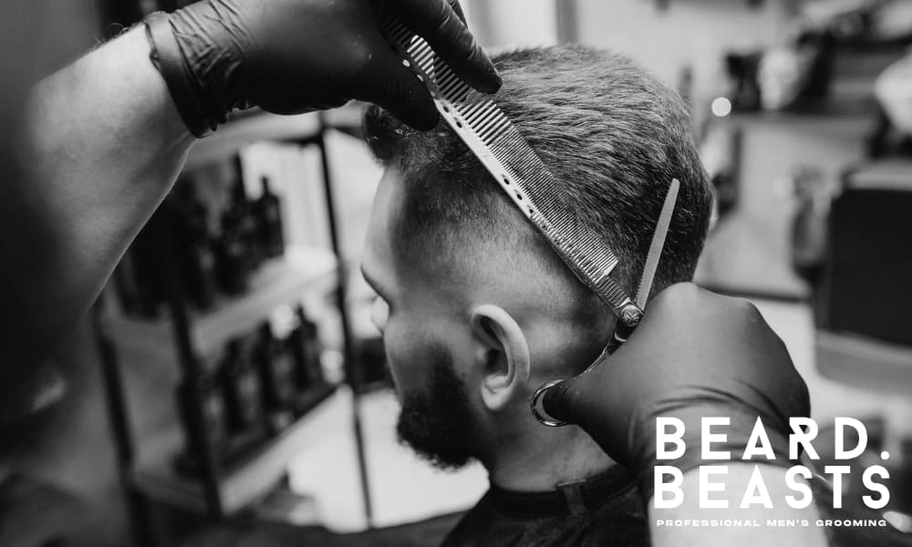 Barber giving a precise low fade haircut to a man at a modern barbershop, showcasing clean grooming techniques — Beard Beasts professional men's grooming.