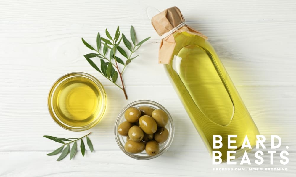 Top view of a bottle and bowl of olive oil with fresh olives and olive branches—an effective natural hair clipper oil alternative for lubrication and rust prevention