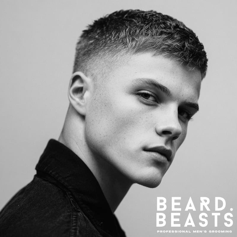 Young man with a short textured crop and fade, featuring clean, sharp layers on top and a well-defined fade on the sides for a neat, modern look.