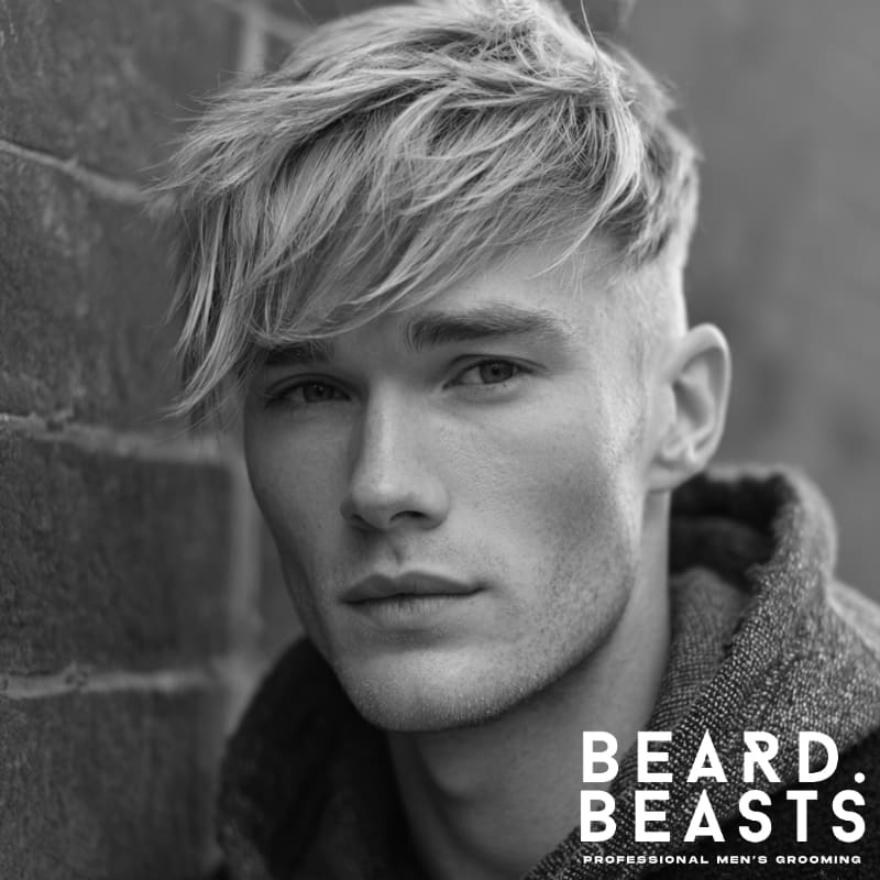 A stylish side-swept fringe hairstyle, with textured hair falling across the forehead for a relaxed, yet modern look. The volume and length on top create a soft, flattering appearance, adding movement and a natural flow to the overall style.