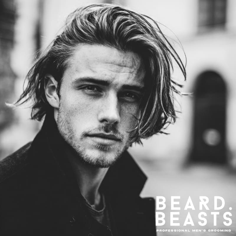 Handsome male model with a modern men's flow haircut, styled with natural volume and loose waves. A fresh, dynamic version of the classic men's flow hairstyle with straight hair.