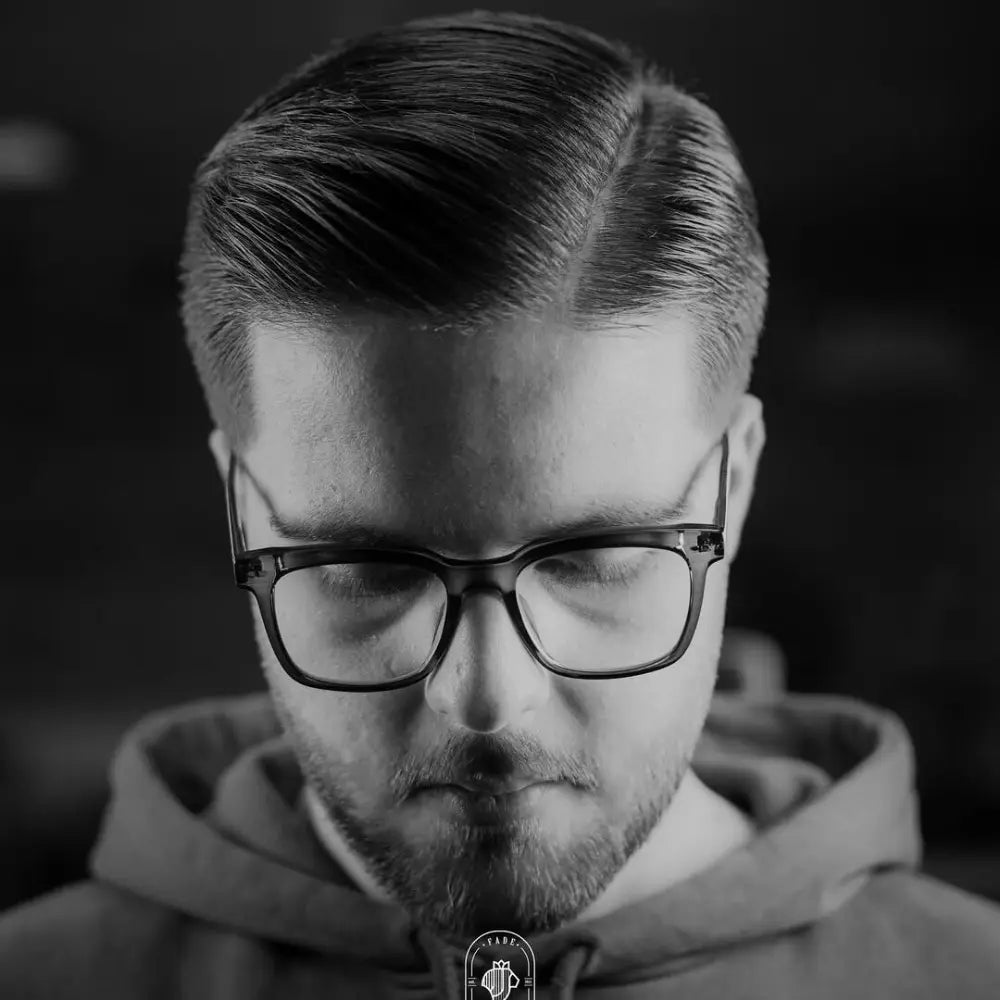 Man with a comb over and taper fade haircut, featuring neatly parted hair on top with a smooth, gradual fade at the sides for a sharp and versatile style.