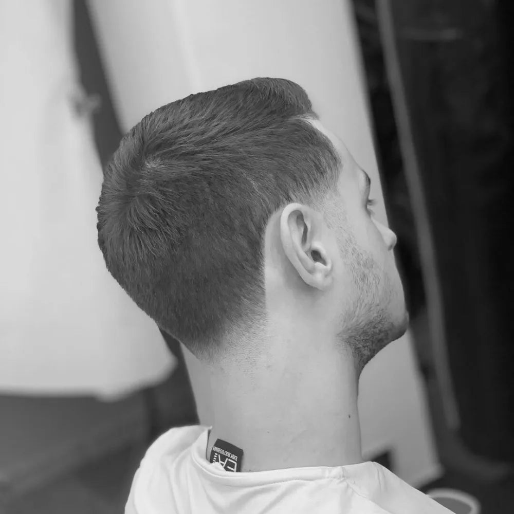 Man with a crew cut and taper fade, featuring short, evenly trimmed hair on top with a gradual fade at the neckline and sideburns for a clean, low-maintenance style.