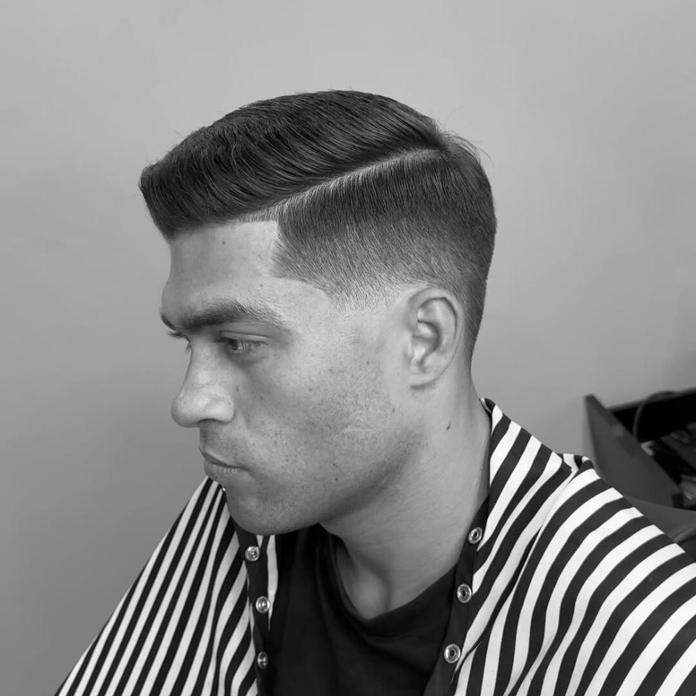 Man with a taper fade and side part haircut, featuring neatly combed hair on top with a gradual fade at the sides for a clean, professional look.