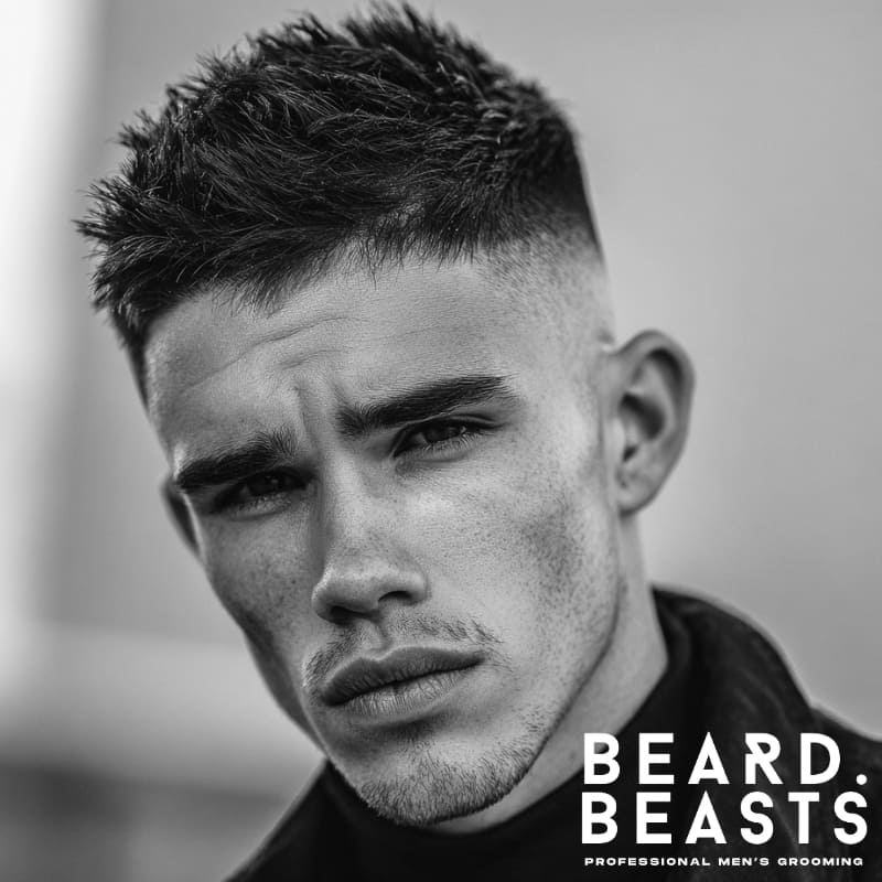 A modern textured fade hairstyle for men with a diamond face shape, featuring short, spiky texture on top with a clean fade on the sides. This hairstyle enhances the angular features of a diamond-shaped face, providing a bold, stylish look with sharp definition.