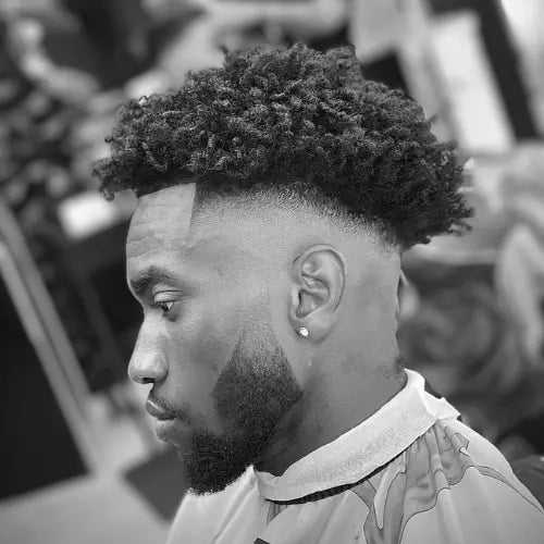 A stylish twists drop fade haircut featuring a seamless fade that curves around the head, blending into voluminous, well-defined twists on top. The sharp lineup and precisely shaped beard enhance the clean and modern look, making this fade haircut a bold and fashionable choice for men seeking a fresh and trendy style.