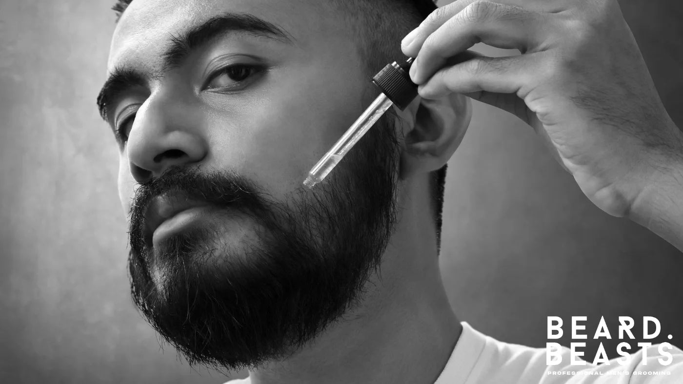 Man applying beard oil with a dropper to moisturize and soften his wiry beard..