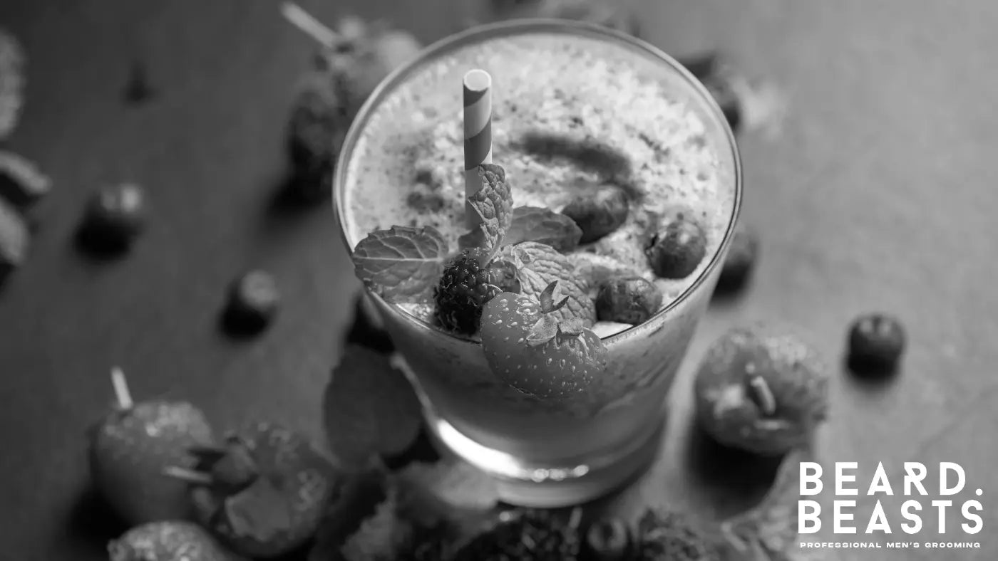 A glass of mixed berry smoothie topped with strawberries, blueberries, and mint, a nutrient-rich drink packed with vitamins that support beard growth and overall follicle health.