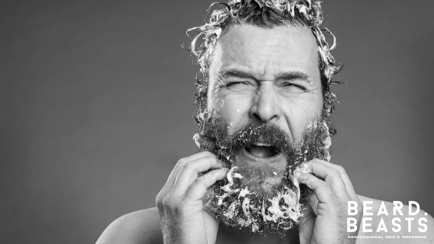 Man applying shampoo and working lather through his beard during grooming.
