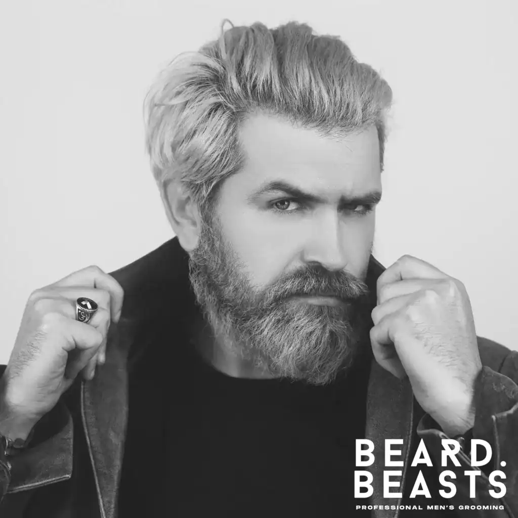 Bearded man with blonde hair styled using matte clay, wearing a brown leather jacket and looking confidently at the camera.