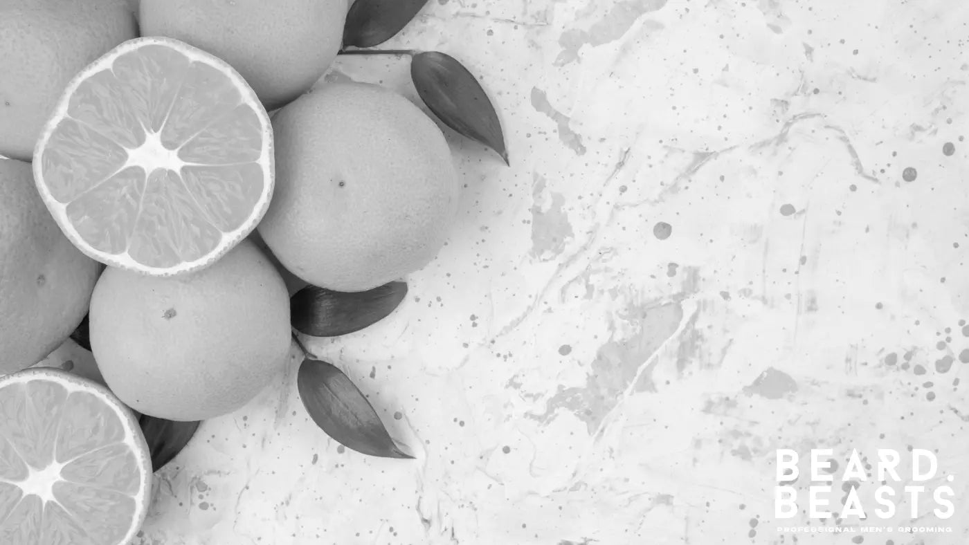 Fresh oranges on a light marble surface with green leaves, highlighting a vitamin C-rich fruit that supports collagen production and promotes healthy beard growth.