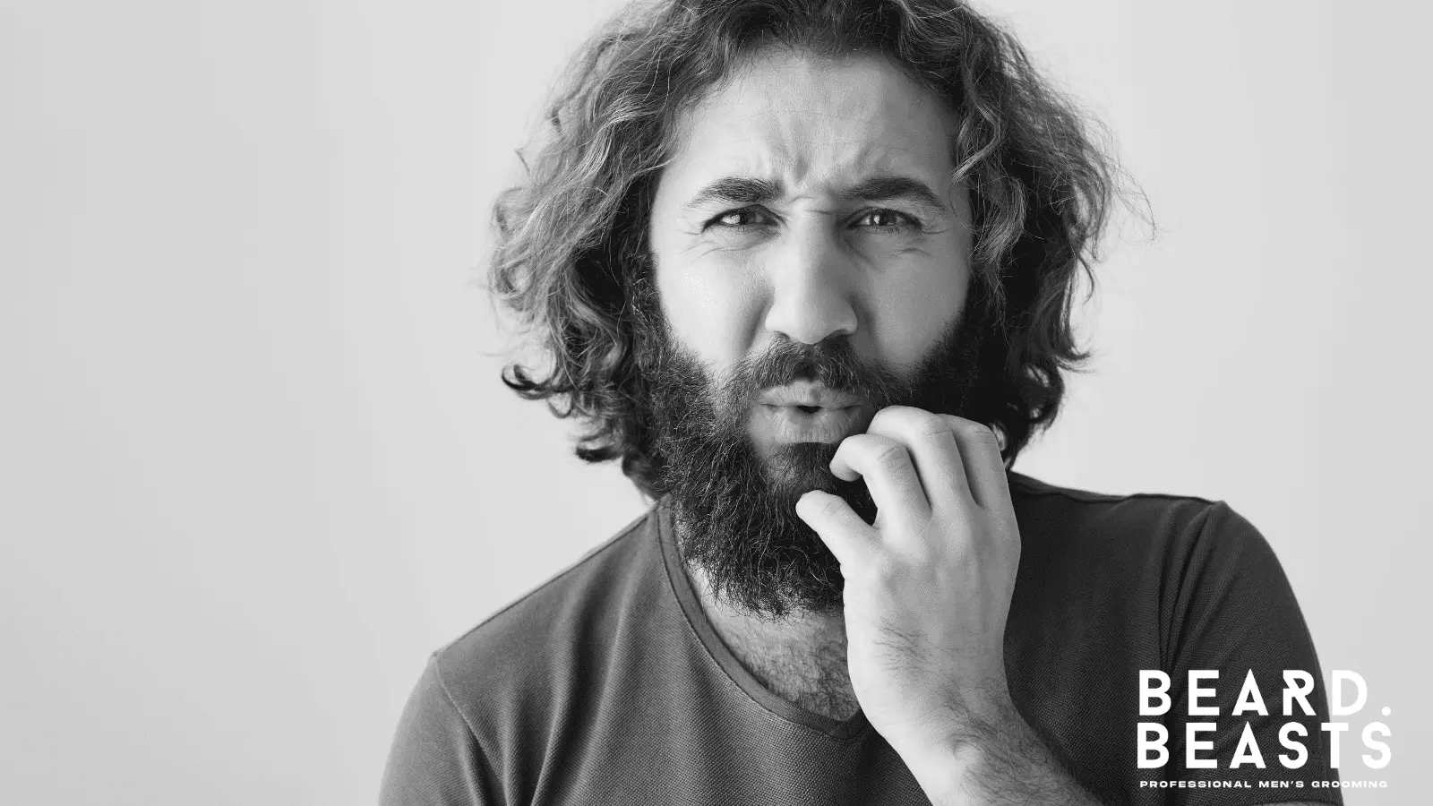 Man experiencing beard itch and irritation while scratching his beard