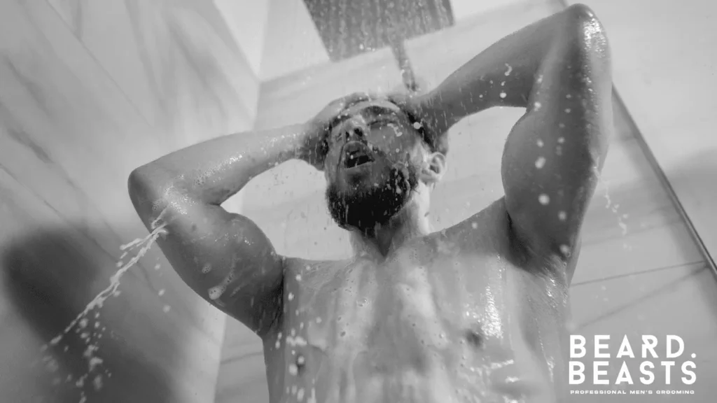 Man washing beard in hot shower, a common cause of dry skin and beard flakes without itch