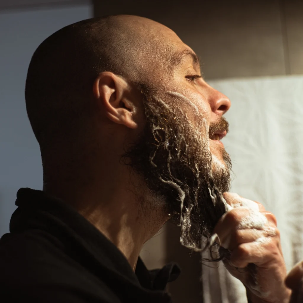 Man gently washing his beard with beard wash in the bathroom.
