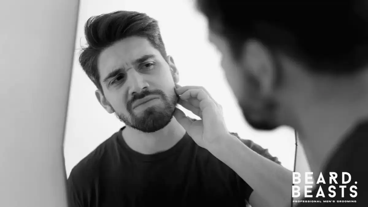 Man inspecting his beard in the mirror for beard flakes