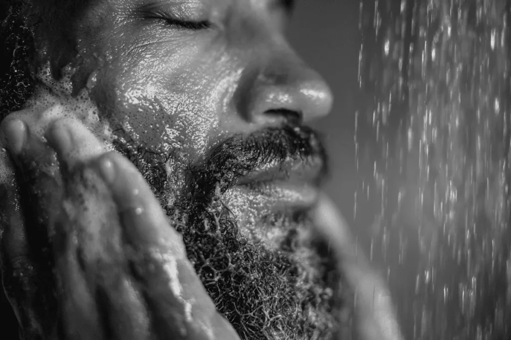 A close-up of a man lathering his beard with wash and water to remove excess oil and product buildup.