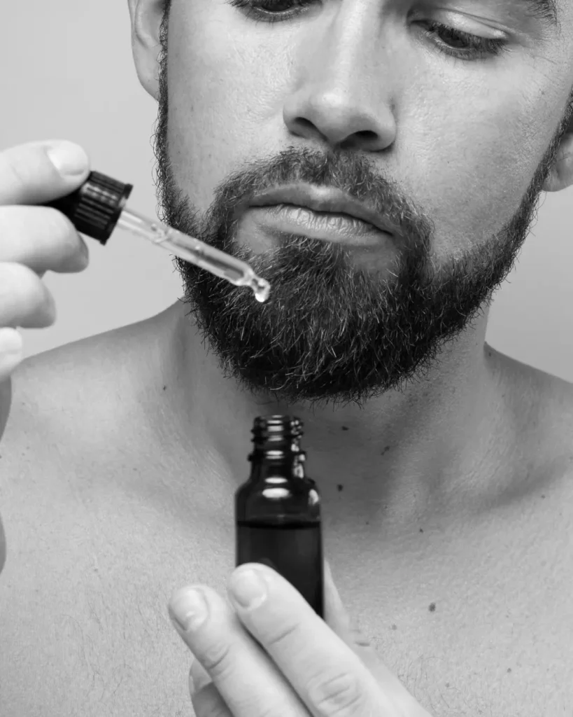 Man applying beard oil with a dropper, showing how beard oil can help reduce dryness and friction that lead to beard breakage.