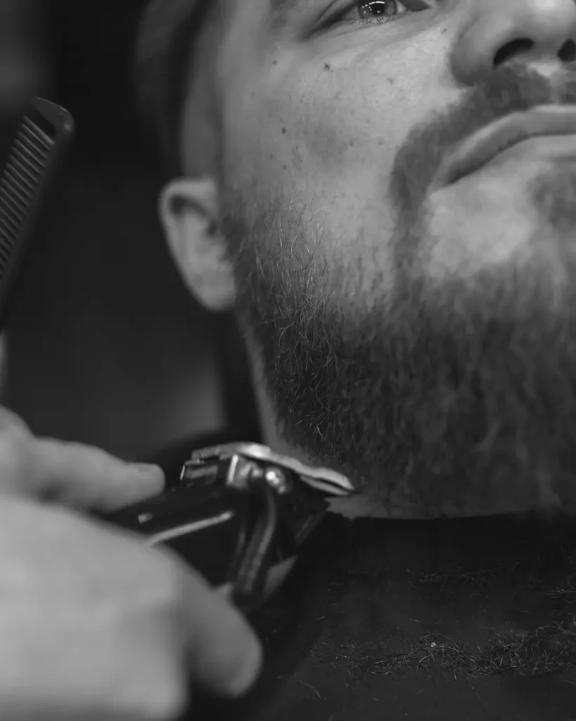 Barber trimming a man’s beard and neckline ahead of an engagement proposal
