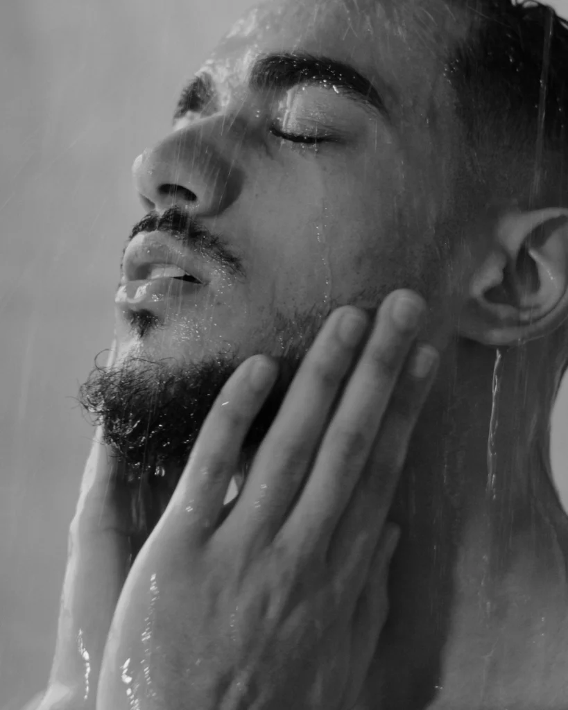 Man washing his beard in the shower, showing how a beard wash should clean the beard and skin underneath without leaving the hair dry or tight.