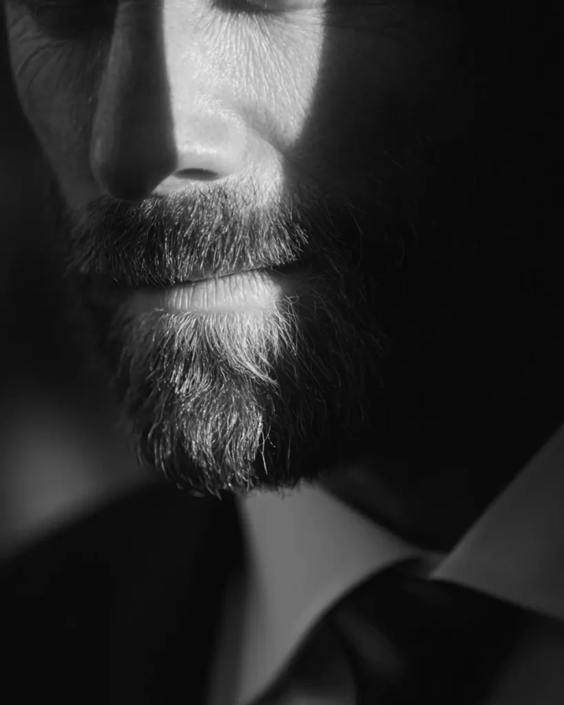 Close-up of a man with a full beard wearing a suit and tie