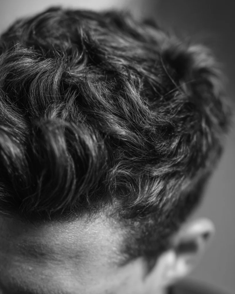 Close-up of textured men’s hair, showing why hair type and natural movement matter when choosing between a side part and middle part.