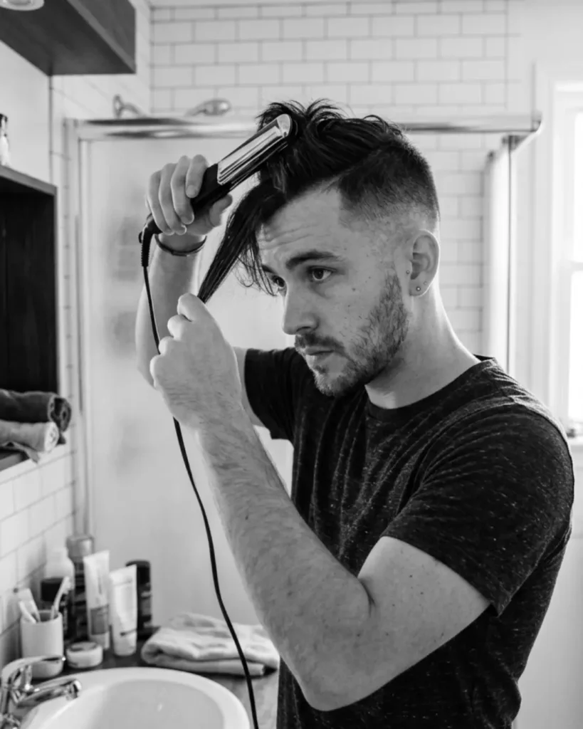 Man straightening the front section of his hair with a flat iron
