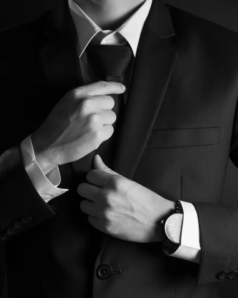 Man adjusting his tie while wearing a dark suit for an engagement proposal