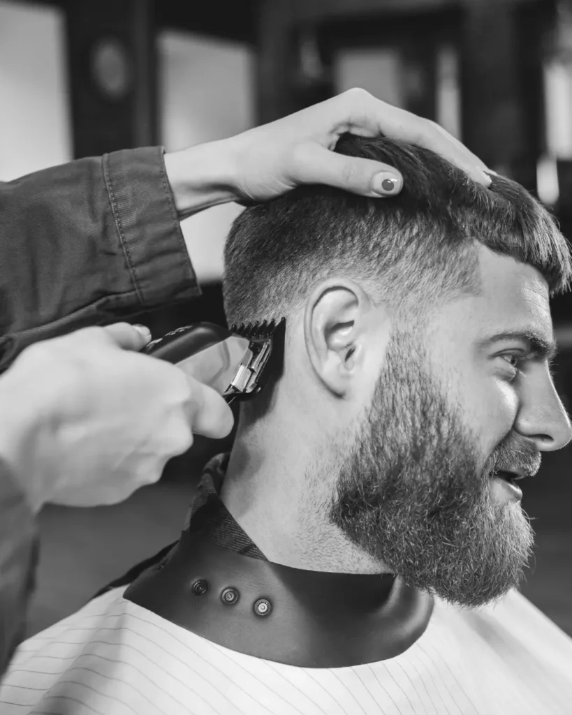 Barber giving a bearded man a fade haircut several days before his proposal