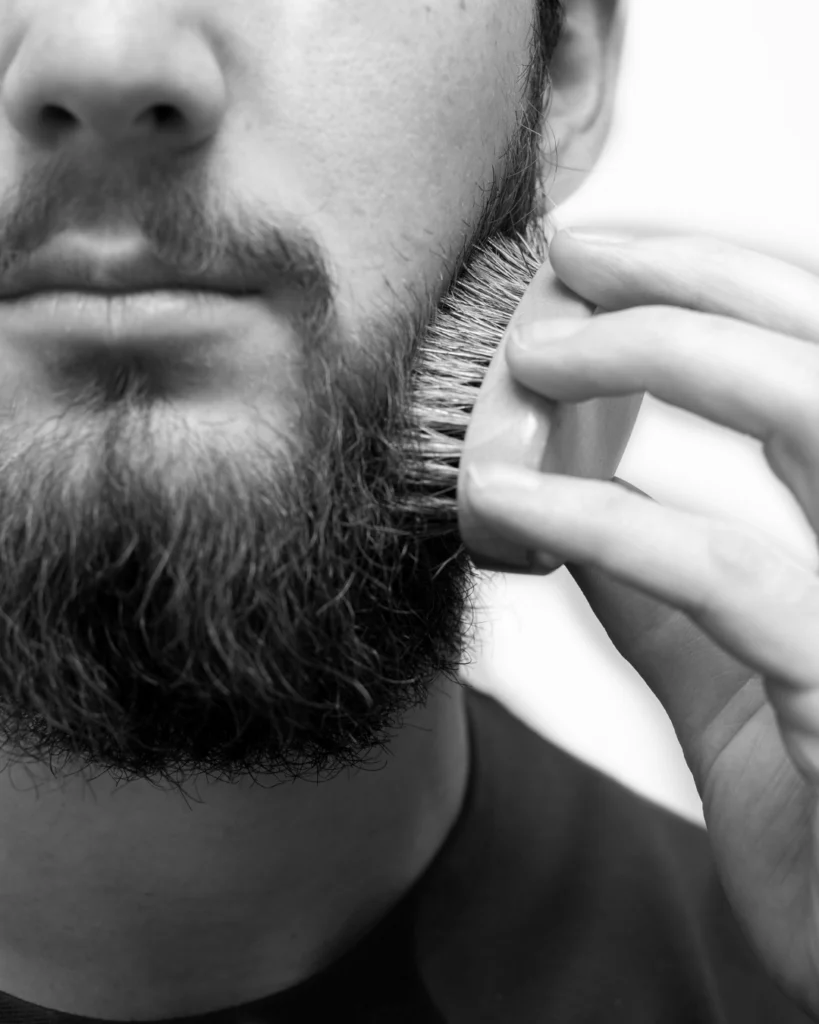 Man brushing a patchy beard, showing how grooming can help uneven facial hair look better but cannot fix true beard hair loss.